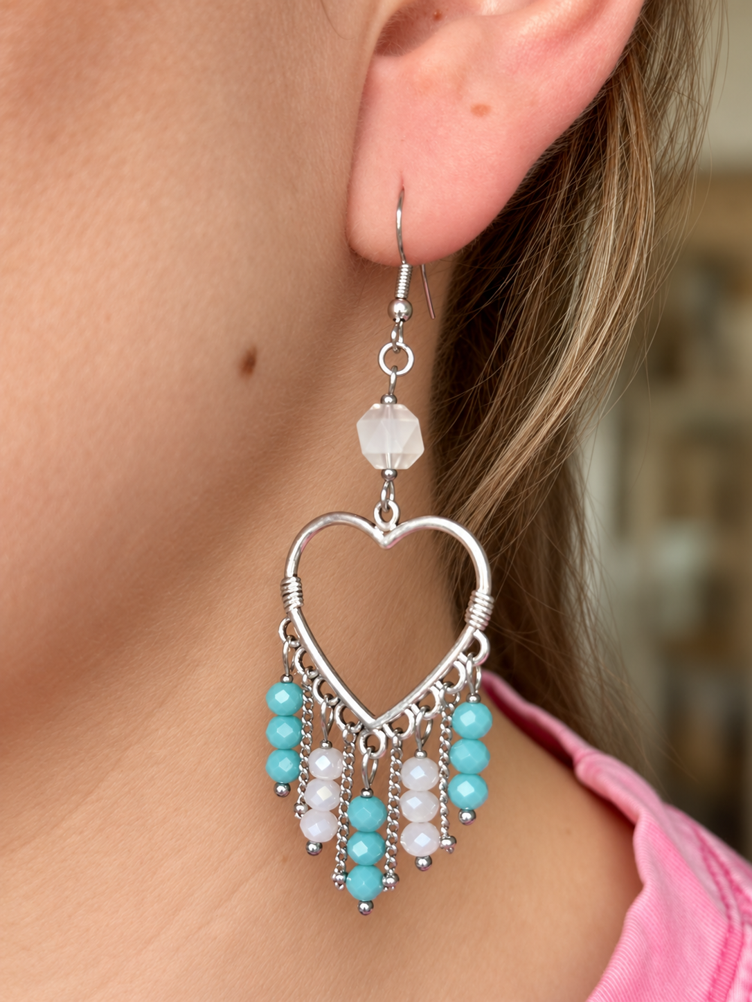 These playful earrings feature silver-tone heart outlines with dangling chains and faceted blue and white beads. The beads move gently as you wear them, adding a soft touch of colour to an everyday outfit or a special occasion look.