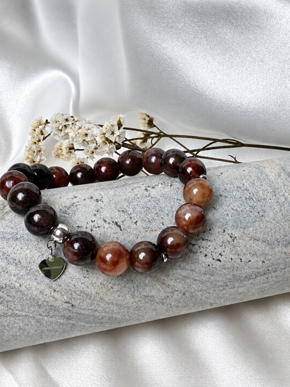 A handmade bracelet featuring stone in rich brown, burgundy and honey tones, complemented by silver-tone accents and a delicate heart charm. A warm, elegant design for everyday wear.

Stone size: 10 mm
Bracelet size: approximately 17–17.5 cm