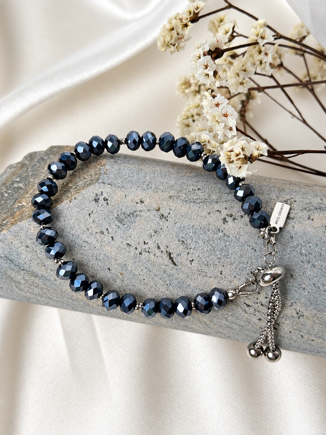 A handmade bracelet featuring faceted glass crystal beads in deep midnight blue with a metallic shimmer, complemented by silver-tone details. An elegant design, perfect worn alone or layered with other bracelets.

Bead size: 6 mm
Bracelet length: approximately 17 cm + 3.5 cm extension chain
