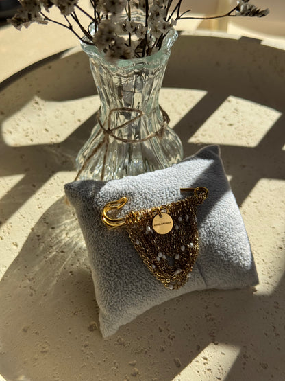 A handmade brooch with layered gold-tone chains, small white beads and an Angel Dreamer charm. The draped chains give it a soft, elegant look. Pin it to a blazer, coat or dress for a distinctive finishing touch.
The brooch measures approximately 5 × 5 cm