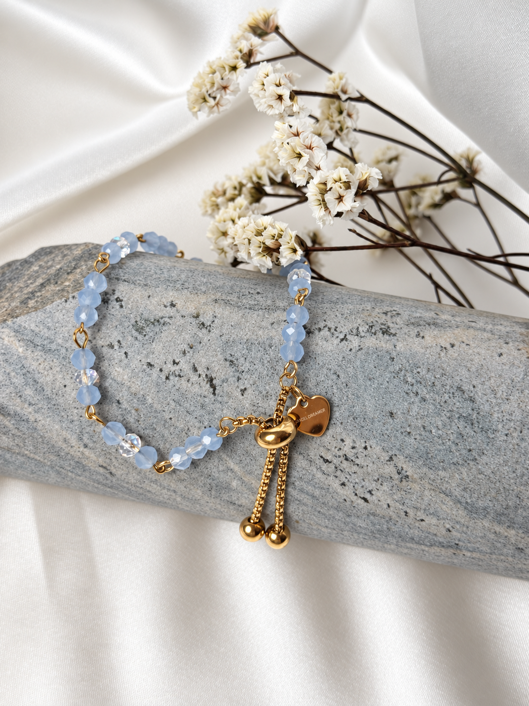 A handmade bracelet featuring faceted glass crystal beads in soft blue with shimmering clear accents, linked with gold-tone details and finished with a delicate heart charm. An elegant design, perfect worn alone or layered with other bracelets.

Bead size: 4 mm
Bracelet length: approximately 17 cm + 3.5 cm extension chain