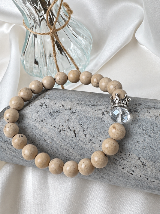 A handmade bracelet featuring stone in warm beige tones, a clear faceted accent and a silver-tone crown detail. An elegant design, perfect worn alone or stacked with other bracelets.

Stone size: 8 mm
Bracelet size: approximately 18 cm