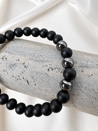 A handmade bracelet featuring matte onyx and polished hematite accents. A minimalist design combining deep black tones with a subtle metallic shine for everyday wear.