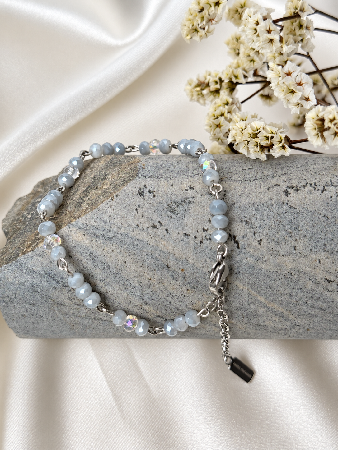 A handmade bracelet featuring faceted glass crystal beads in soft grey tones with shimmering clear accents, linked with stainless steel details. A delicate, elegant design, perfect worn alone or layered with other bracelets.

Bead size: 4 mm
Bracelet length: approximately 18 cm + 4 cm extension chain