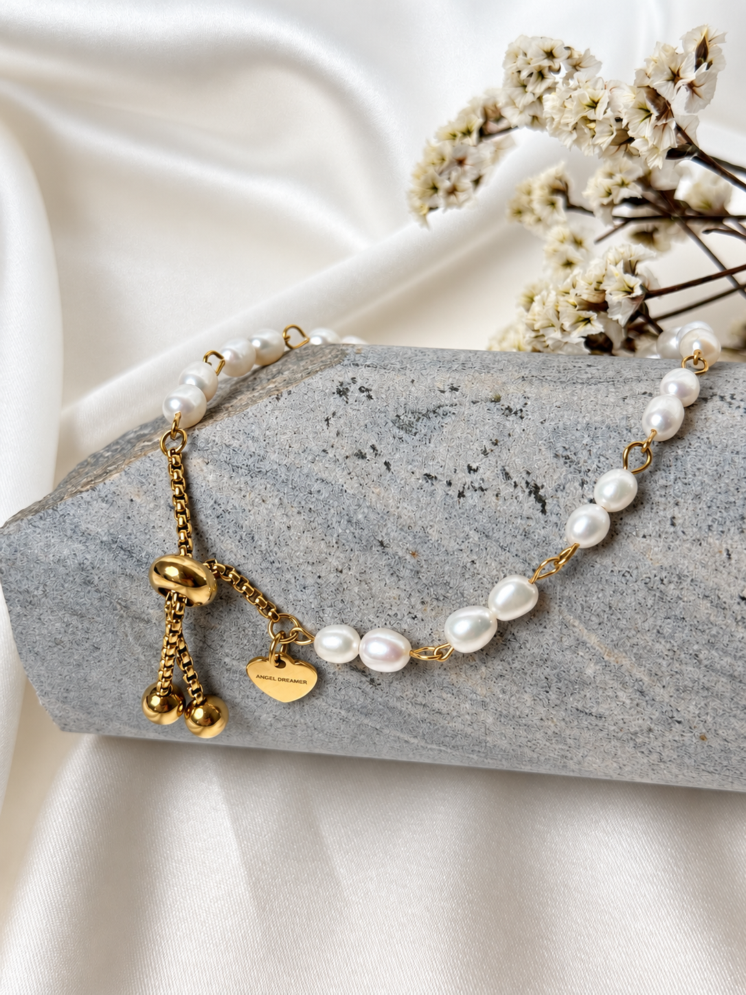 A handmade bracelet featuring lustrous white pearls linked with gold-tone stainless steel details and finished with a delicate heart charm. A timeless, elegant design with an adjustable chain for a comfortable fit.

Bracelet length: approximately 17 cm + 3.5 cm extension chain