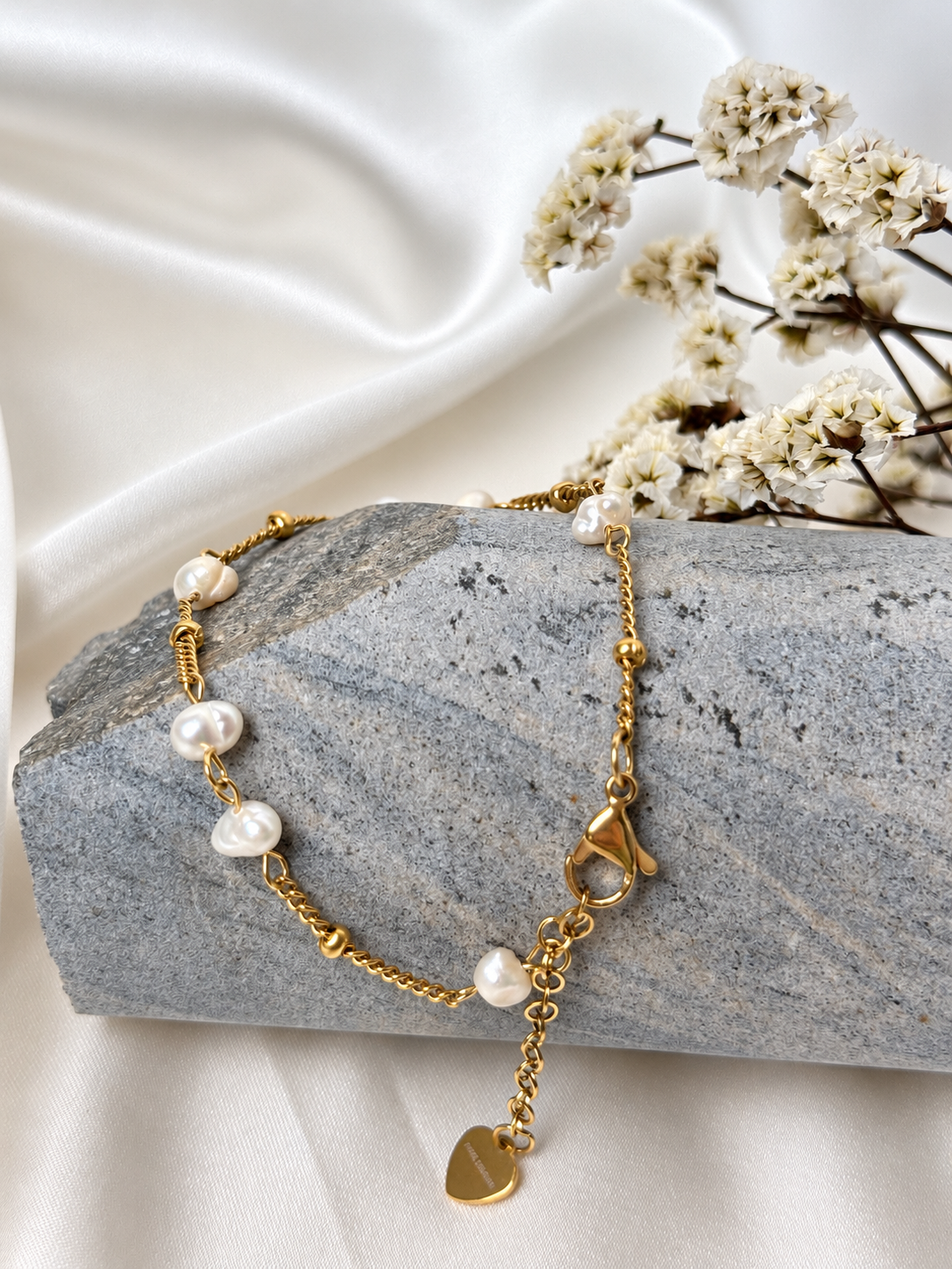 A handmade bracelet featuring freshwater pearls and a delicate gold-tone stainless steel chain, finished with a heart charm. A refined, elegant design, perfect worn alone or layered with other bracelets.

Bracelet length: approximately 17 cm + 4 cm extension chain