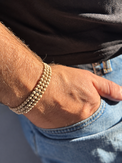 A handmade three-strand bracelet featuring stone in soft beige and warm earthy tones. An elegant design finished with subtle silver-tone details.

Stone size: 4 mm
Bracelet size: approximately 20–20.5 cm