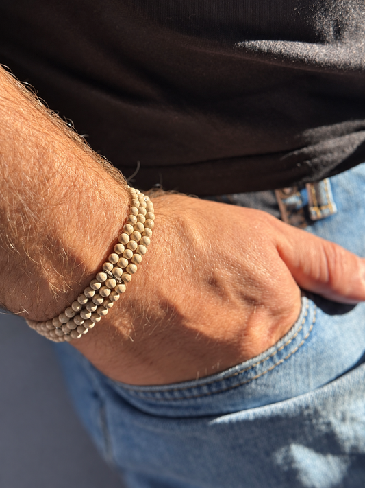 A handmade three-strand bracelet featuring stone in soft beige and warm earthy tones. An elegant design finished with subtle silver-tone details.

Stone size: 4 mm
Bracelet size: approximately 20–20.5 cm