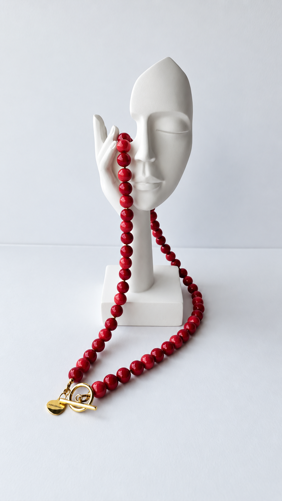 A vibrant necklace featuring round beads in rich red and coral tones, finished with a decorative gold-tone toggle clasp at the front.

The beaded pendants can be easily removed and swapped, allowing you to personalise your look. Wear it with a pendant for an expressive touch or without one for a simpler style.

Total necklace length: 48 cm.
