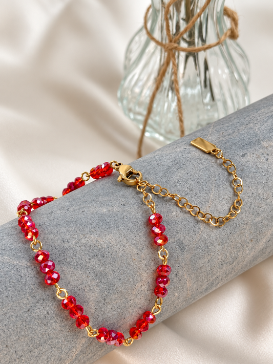 A delicate handmade bracelet featuring faceted red beads arranged in groups of three and joined by gold-tone links. The beads catch the light beautifully, adding a vibrant touch to everyday outfits or special occasions. Wear it alone for a subtle accent or layer it with other bracelets.

 Length adjustable from 18 to 23 cm.