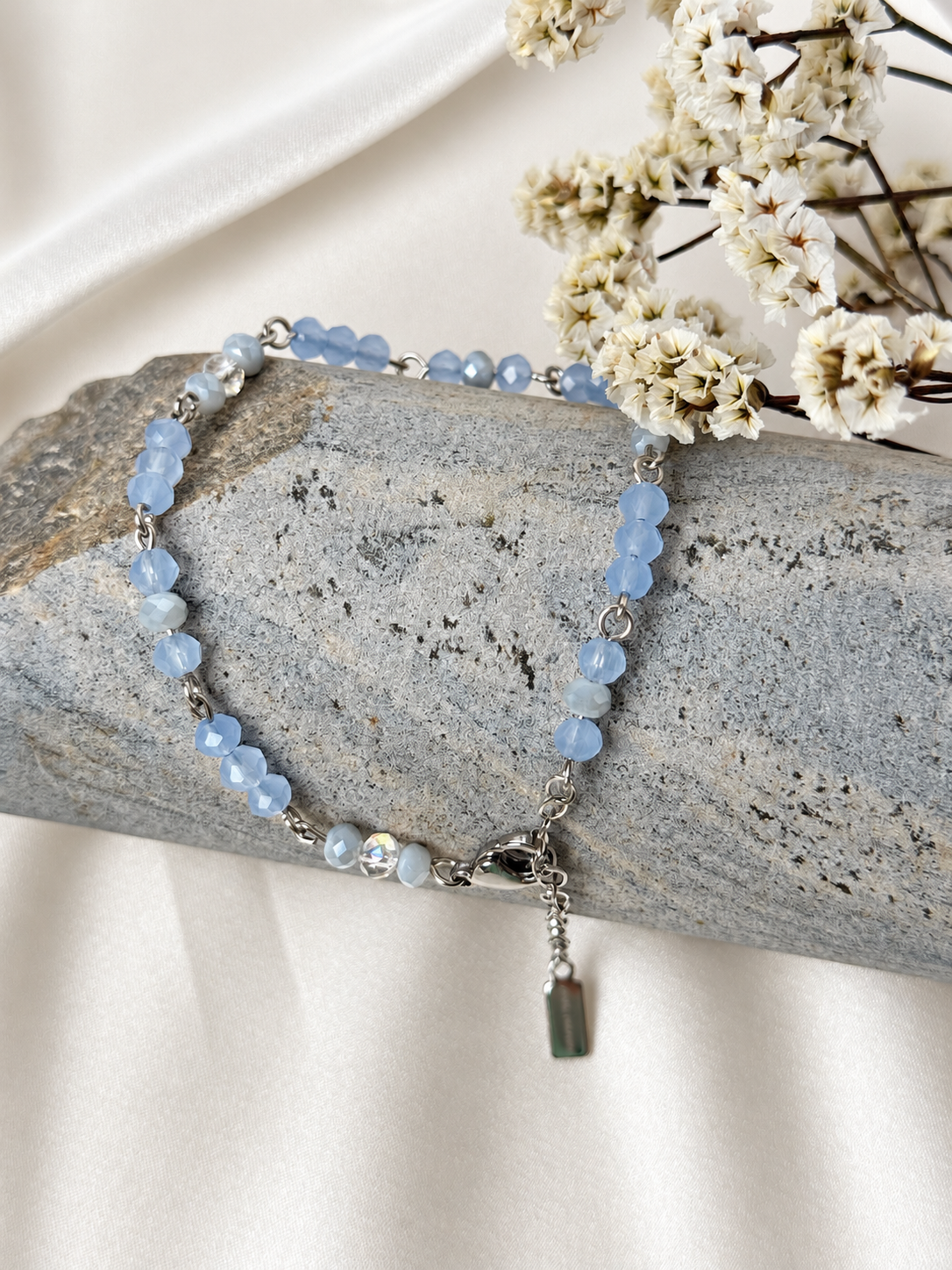 A handmade bracelet featuring faceted glass crystal beads in soft blue tones with shimmering clear accents, linked with stainless steel details. A delicate, elegant design, perfect worn alone or layered with other bracelets.

Bead size: 4 mm
Bracelet length: approximately 18 cm + 4 cm extension chain